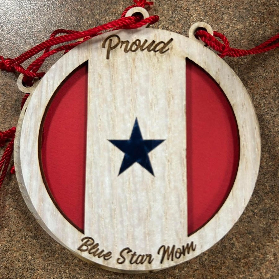 Proud Blue Star Mom Ornament - Legacy Images - Round white wood ornament engraved with Proud at the top and Blue Star Mom at the bottom. Single blue foil star in middle with red on either side.